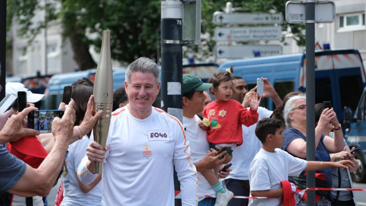 Nine boss Mike Sneesby carrying the Olympic torch in Paris in July.