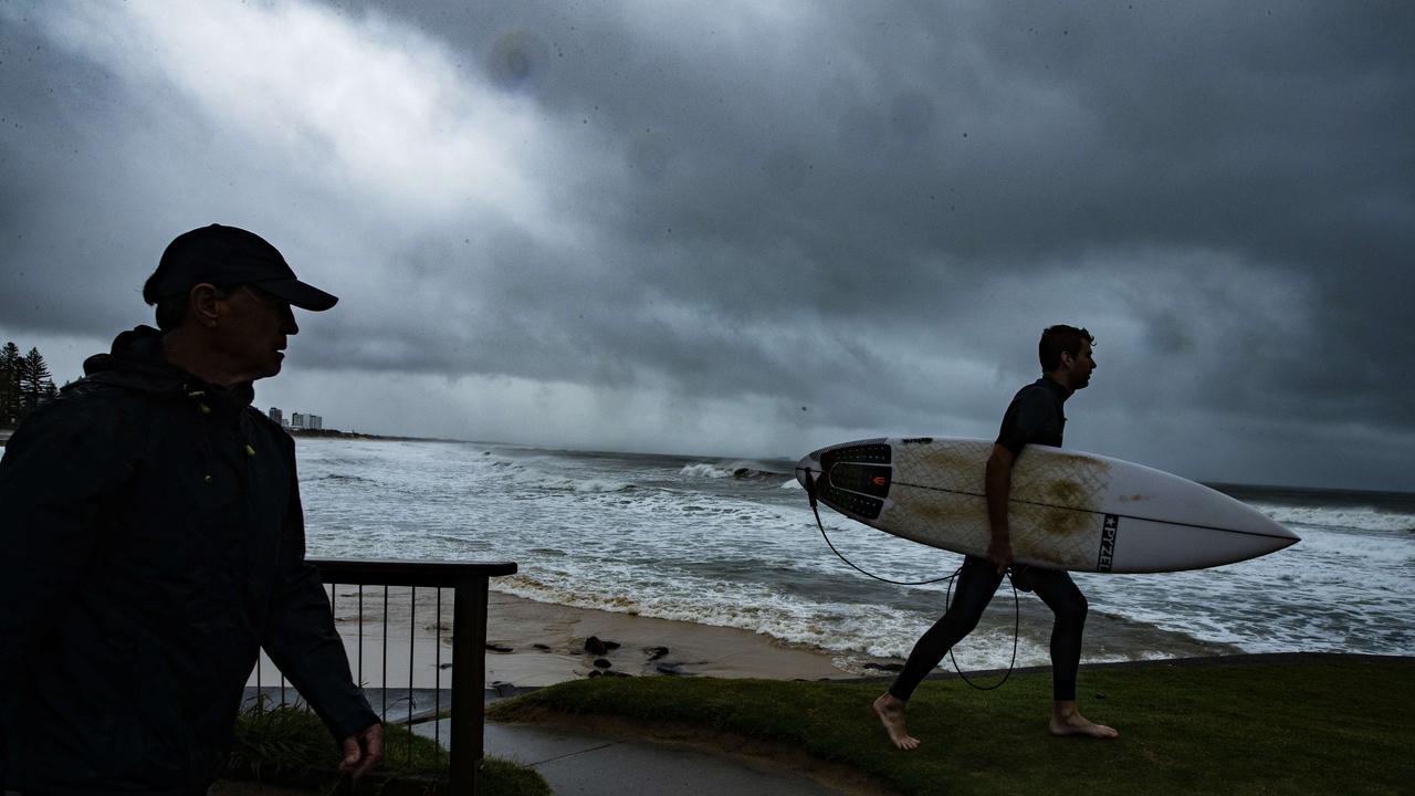 Morning walkers and surfers brave the rain at Alexandra Headland on Sunday as an the effects of an east coast low hit South East Queensland. Picture: Lachie Millard