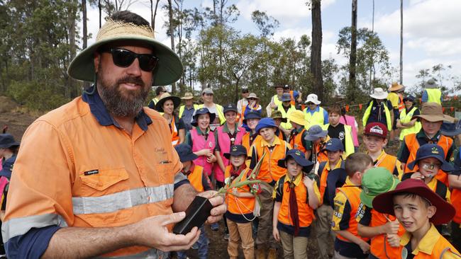 Ben Nottidge, senior ecologist, with Albany Creek Scouts during the tree planting initiative at the Warner Quarry site which is becoming a housing development. (AAP Image/Regi Varghese)