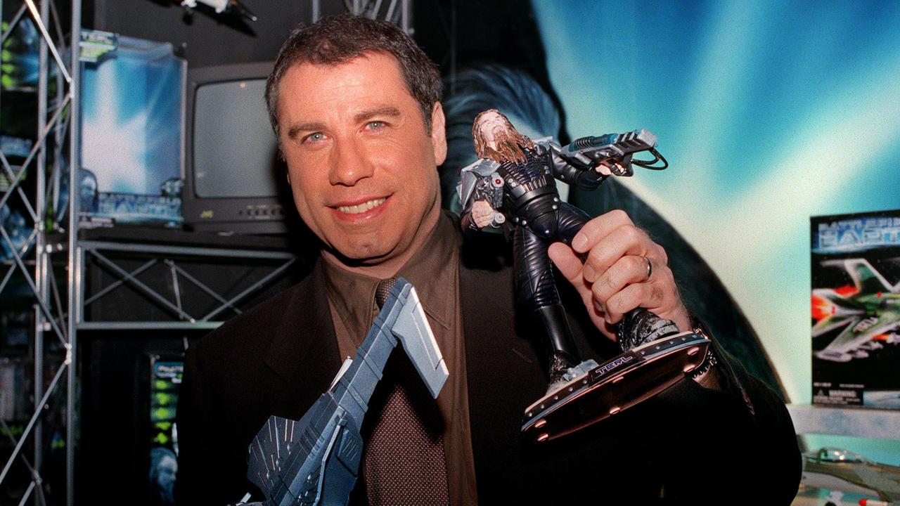 John Travolta holding a piece of merchandise from Battlefield Earth.