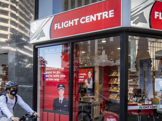 A cyclist rides past a Flight Centre store wearing a mask to protect themselves from Covid-19, Brisbane, Friday, May 1, 2020. (AAP Image/Glenn Hunt) NO ARCHIVING
