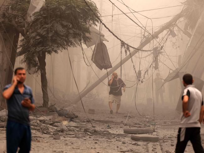 Palestinians inspect the destruction in a neighbourhood heavily damaged by Israeli air strikes on Gaza City's Shati refugee camp. Picture: Mahmud Hams/AFP