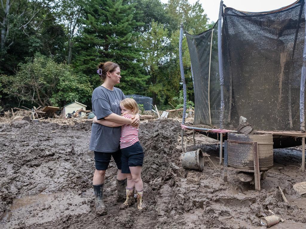 Taylah Bleakley and her six-year-old daughter Thielen amid the wreckage of their backyard in Wingham caused by the recent flood. Picture Thomas Lisson