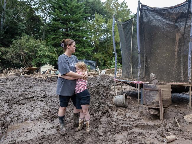 Taylah Bleakley and her six-year-old daughter Thielen amid the wreckage of their backyard in Wingham caused by the recent flood. Picture Thomas Lisson