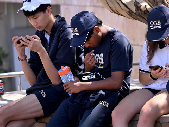 TOPSHOT - Students look at their phones in Melbourne on November 28, 2024 as Australia looks to ban children under 16 from social media with claims social media platforms have been tarnished by cyberbullying, the spread of illegal content, and election-meddling claims. Australia is among the vanguard of nations trying to clean up social media, and the age limit legislation will make it among the world's strictest measures aimed at children. (Photo by William WEST / AFP)