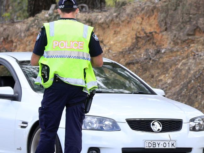 BURLEIGH WEST , AUSTRALIA - NewsWire Photos March 31, 2021: Uniformed Queensland Police traffic officers wearing face masks stop and check vehicles east bound on West Burleigh Road, Burleigh West .Picture: NCA NewsWire / Scott Powick