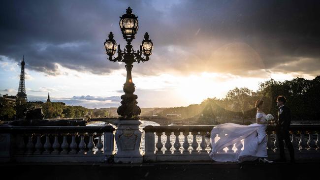 A newlywed couple pose at sunset on the Alexandre III bridge in front of the Eiffel Tower in Paris. Picture: Julien De Rosa/AFP