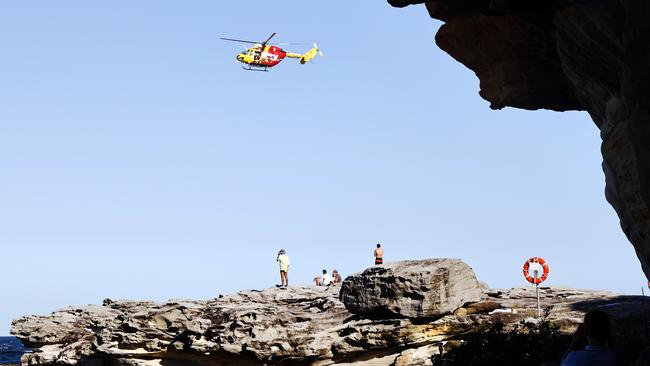 A rescue helicopter and onlookers near the scene of the shark attack on Wednesday. Picture: Richard Dobson