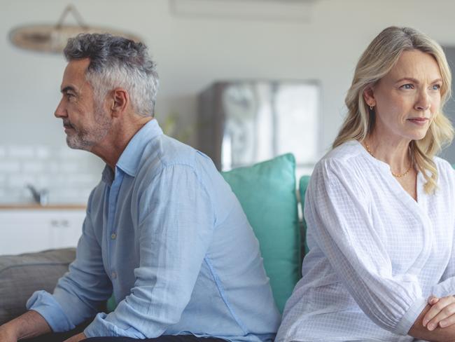 Mature couple fighting at home sitting on the sofa. They are sitting back to back not talking; divorce middle-aged couple argument generic
