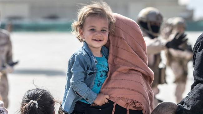 A child smiles as she awaits to board as US flight during an evacuation at Hamid Karzai International Airport, Kabul. Picture: AFP