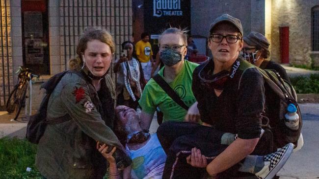 An injured woman is carried by other protesters during clashes with police outside the Third Police Precinct on Wednesday. Picture: AFP