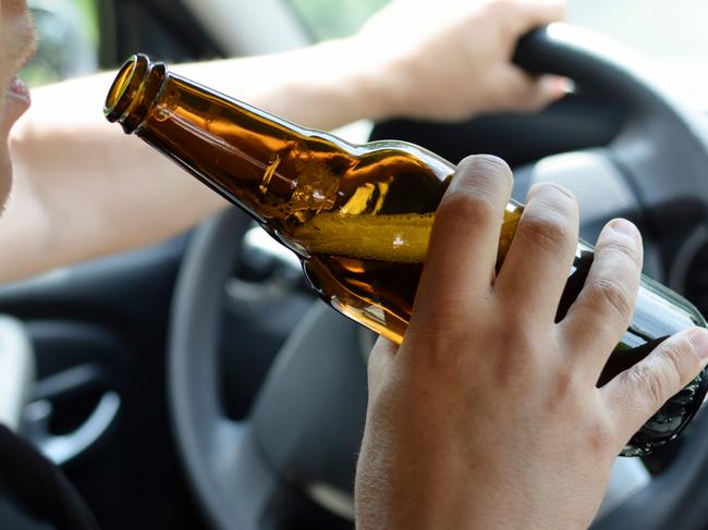 The concept of alcohol driving crime - closeup of young male driver hands with steering wheel and bottle of beer. Drink driving generic. Picture: iSTOCK