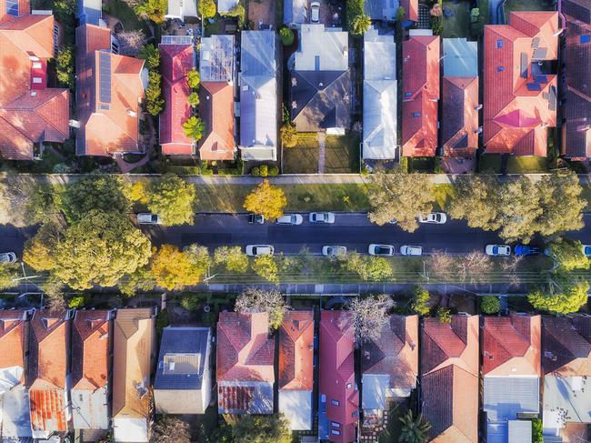 Leafy suburb on Sydney Lower North shore with sky-rocketed real estate property prices - top down aerial view over quiet street between houses with green trees and parked cars. Australian housing generic