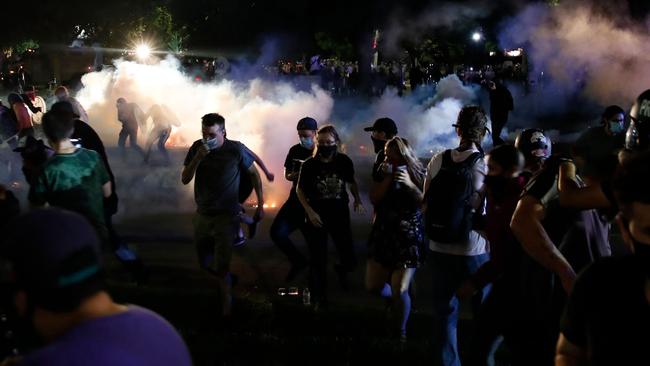 Protesters run for cover as police shoots teargas in an effort to disperse the crowd outside the County Courthouse on August 25. Picture: AFP