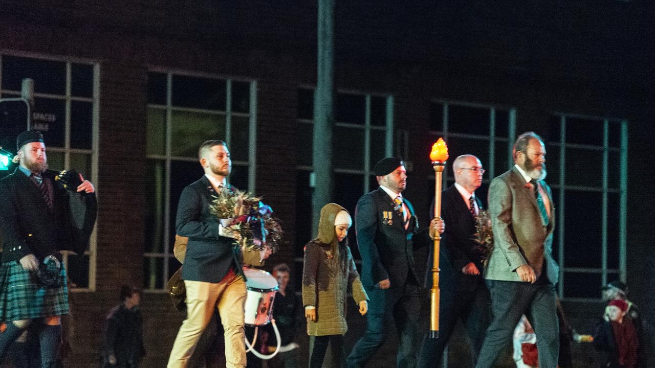 The wreaths and torch are carried through the pre-dawn city streets by Zacharie Wright-Hanson (left), Josh Hawkins and Allan Traise on the march to the Mothers' Memorial for the Anzac Day dawn service, Monday, April 25, 2022. Picture: Kevin Farmer