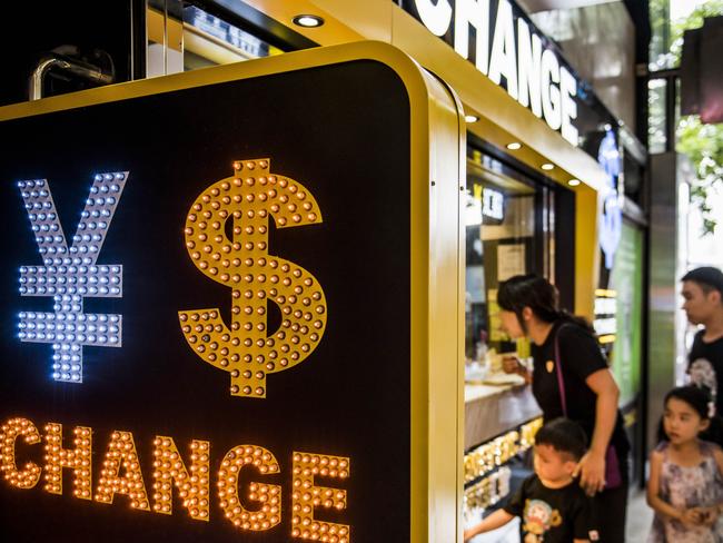 The currency symbol for the Chinese yuan and the dollar is displayed at a currency exchange store in Hong Kong, China, on Wednesday, Aug. 12, 2015. The yuan sank for a second day, spurring China's central bank to intervene as the biggest rout since 1994 tested the government's resolve to give market forces more sway in determining the exchange rate. Photographer: Xaume Olleros/Bloomberg