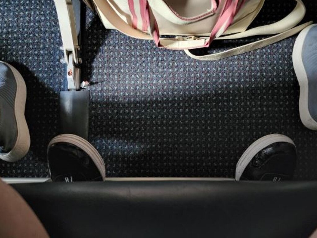 A frustrated passenger shared this photo to Reddit of the person behind them stretching their feet so far out in front, they poked out underneath their seat. Picture: Reddit