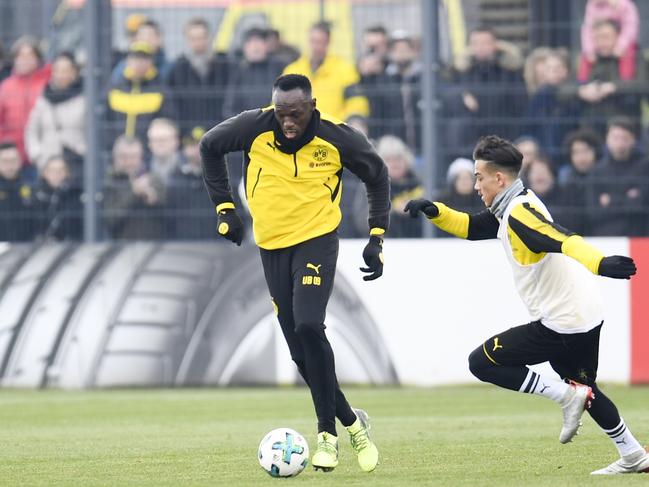 Retired Jamaican Olympic and World champion sprinter Usain Bolt (L) plays the ball as he takes part in a training session of German first Bundesliga football team Dortmund, on March 23, in Dortmund.   Bolt, 31, who holds the world records for the 100m and 200m, had already announced last January that he would be training with Dortmund during the current international break. / AFP PHOTO / Patrik STOLLARZ