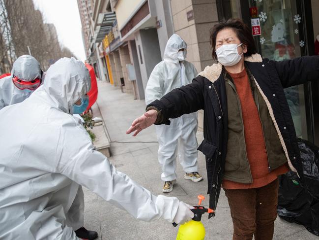 A woman recovered from the COVID-19 infection, is disinfected by volunteers after being discharged from a hospital in Wuhan. Picture: AFP