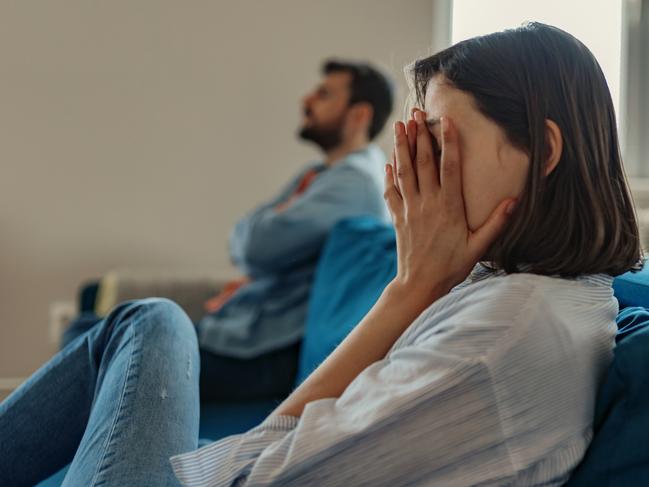 Unhappy Couple After an Argument in the Living Room at Home. Sad Pensive Young Girl Thinking of Relationships Problems Sitting on Sofa With Offended Boyfriend, Conflicts in Marriage, Upset Couple After Fight Dispute, Making Decision of Breaking Up Get Divorced