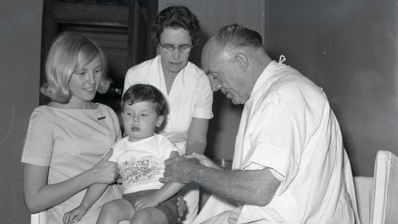 Dr R.V Graham, Brisbane City Council Health Department medical officer, vaccinates Paul Young, 2, of Rocklea, for smallpox in 1962. Assisting was Sister Palma Byrnes, at rear. Picture: Ted Holliday