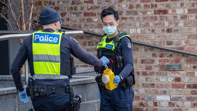 A police officer picks up a used syringe off the ground Picture: Jason Edwards