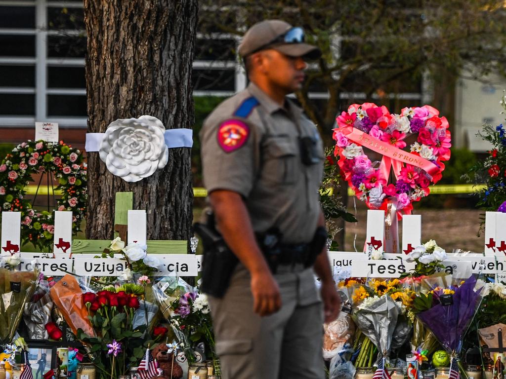 A police officer stands near a makeshift memorial for the shooting victims outside Robb Elementary School in Uvalde, Texas. Picture: AFP