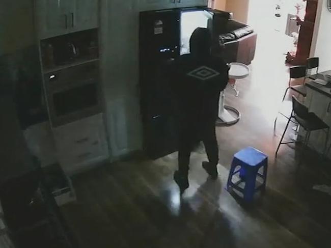 A gang member rummages through the fridge during an aggravated burglary.