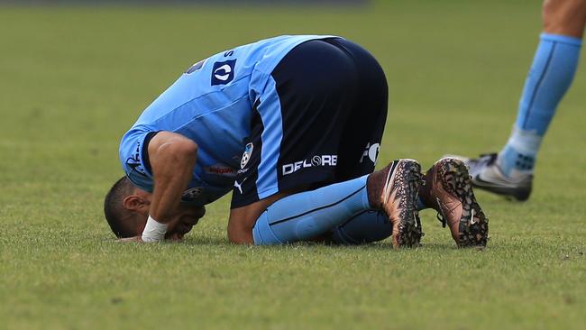 Ali Abbas of Sydney FC celebrates a goal and kisses the turf.