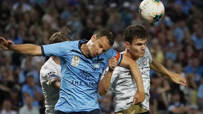 Alex Wilkinson goes up for a header against Curtis Good of Melbourne City.