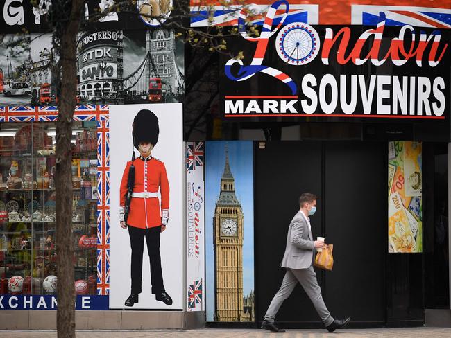 A pedestrian wearing a face covering walks past a souvenir shop, closed due to Covid-19, on Oxford Street in central London.