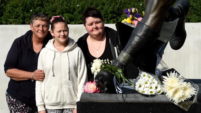 Natalie Fisher, Shelby Fisher and Candice Russell from Perth pay their respects at the Lou Richards statue after his passing yesterday. Picture: Nicole Garmston