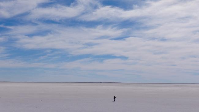 Charles Wooley walks out on to the southern section of Lake Eyre where it is a blinding white, dry salt pan stretching to the horizon during the filming of his program for Channel 7’s Spotlight called The Lake. Picture: Arron Hage