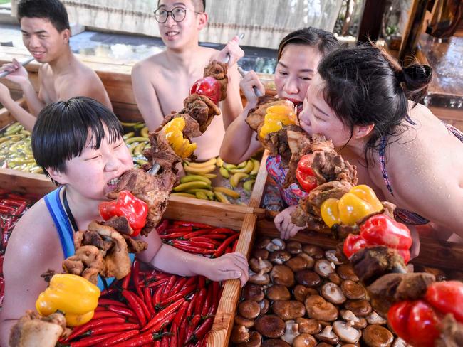 This photo taken on January 27, 2019 shows people enjoying skewered meat while taking a dip in a hotpot-shaped hot spring pool at a hotel in Hangzhou in China's Zhejiang province. - The hot spring is designed to promote a healthy lifestyle in the run-up to the Lunar New Year, or spring festival, which begins the first week of February. (Photo by STR / AFP) / China OUT