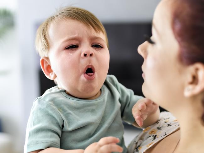 A mother holding child baby on the living room. The baby is sick having some cough