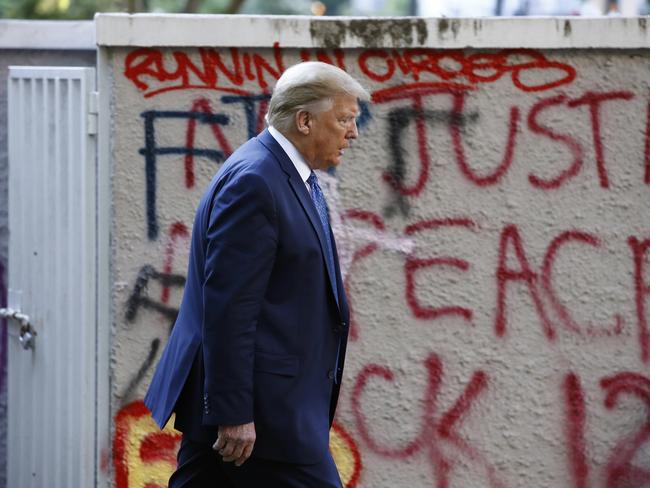 President Donald Trump walks from the White House past graffiti in Lafayette Park to visit St. John's Church in Washington. Picture: AP