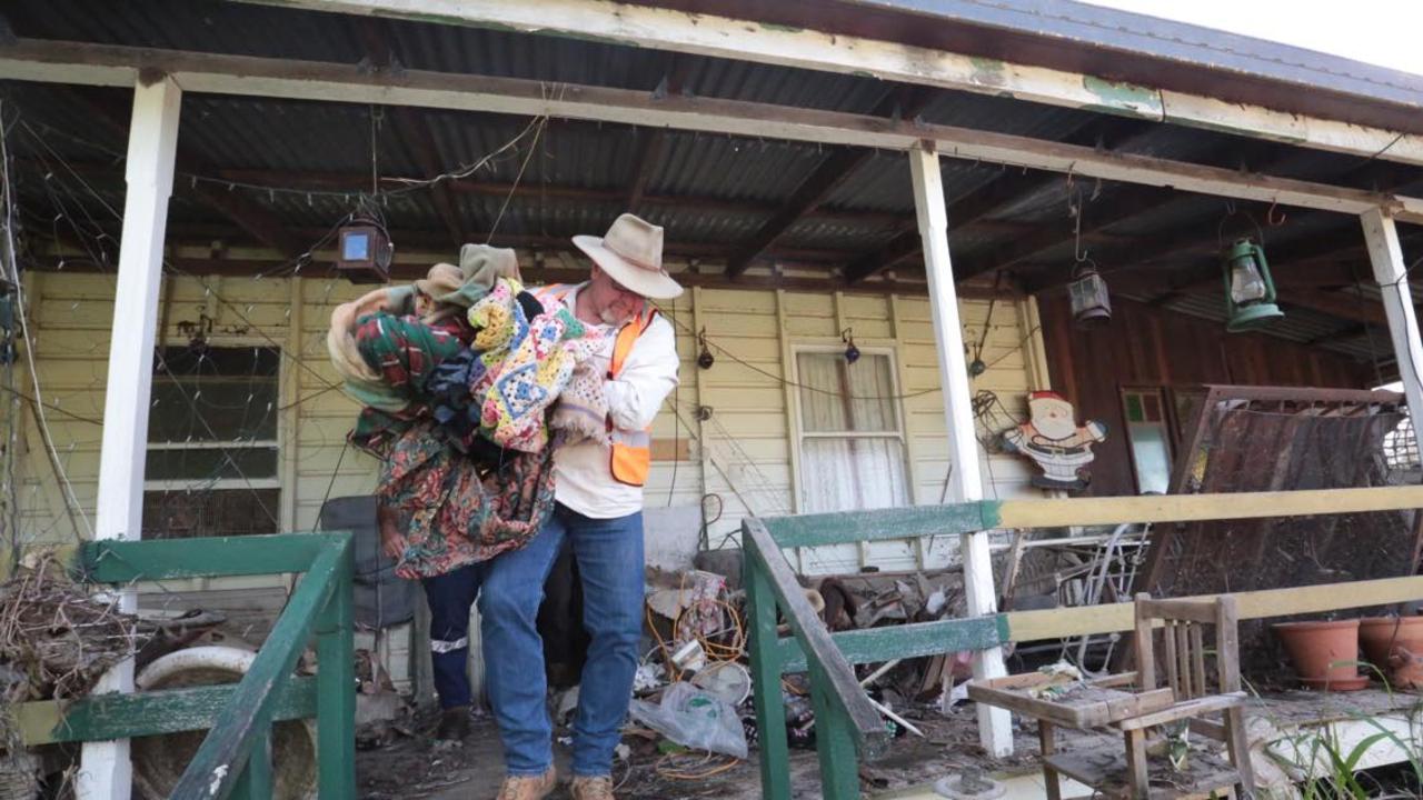 Ken Diehm carrying rubbing from a flood-ravaged home at Brooweena