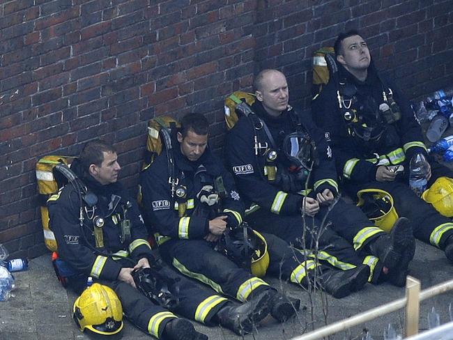 Firefighters rest as they take a break in battling a massive fire that raged in a high-rise apartment building in London. Picture: AP