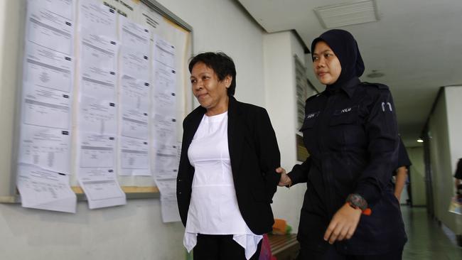Sydneysider Maria Elvira Pinto Exposto (left) is escorted by a police officer to a hearing at Shah Alam High Court in Malaysia on Tuesday. Picture: AP