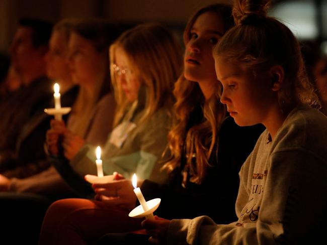 People hold candles during a vigil after a shooting at Oxford High School at Lake Pointe Community Church in Lake Orion, Michigan on November 30, 2021. - A 15-year-old student opened fire at his Michigan high school on November 30, killing three teenagers and wounding eight other people before surrendering to police, authorities said, in what was the deadliest US school shooting so far this year. (Photo by JEFF KOWALSKY / AFP)