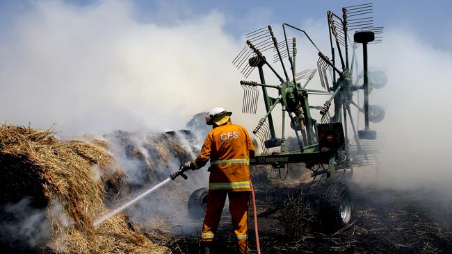 A CFS volunteer houses down a fire which reached Hay bails on a property at Mount Torrens in the Adelaide Hills in Adelaide, Friday, January 3, 2020. Photo: Kelly Barnes/ AAP.