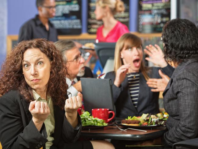 Angry woman with clenched fists at table with coworkers