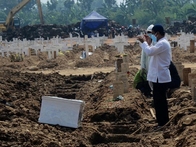 Family members offer prayers during the funeral of a loved one who died from the Covid-19 coronavirus at a cemetery in Jakarta. Picture: AFP