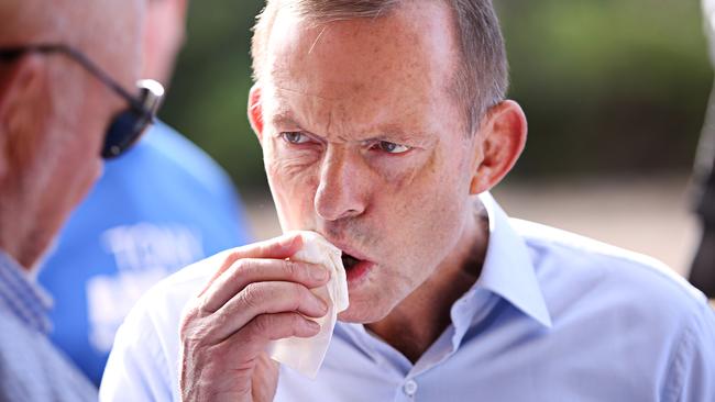 To balance out the bitterness Tony Abbott scoffs down a sausage sanga. Adam Yip/ The Australian