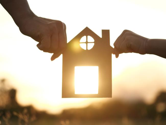 Happy Family, House, and Home concept. Mother and daughter hands holding a paper house, home together silhouette against sunset with soft focus. Concept of Happy Family, life, insurance, care