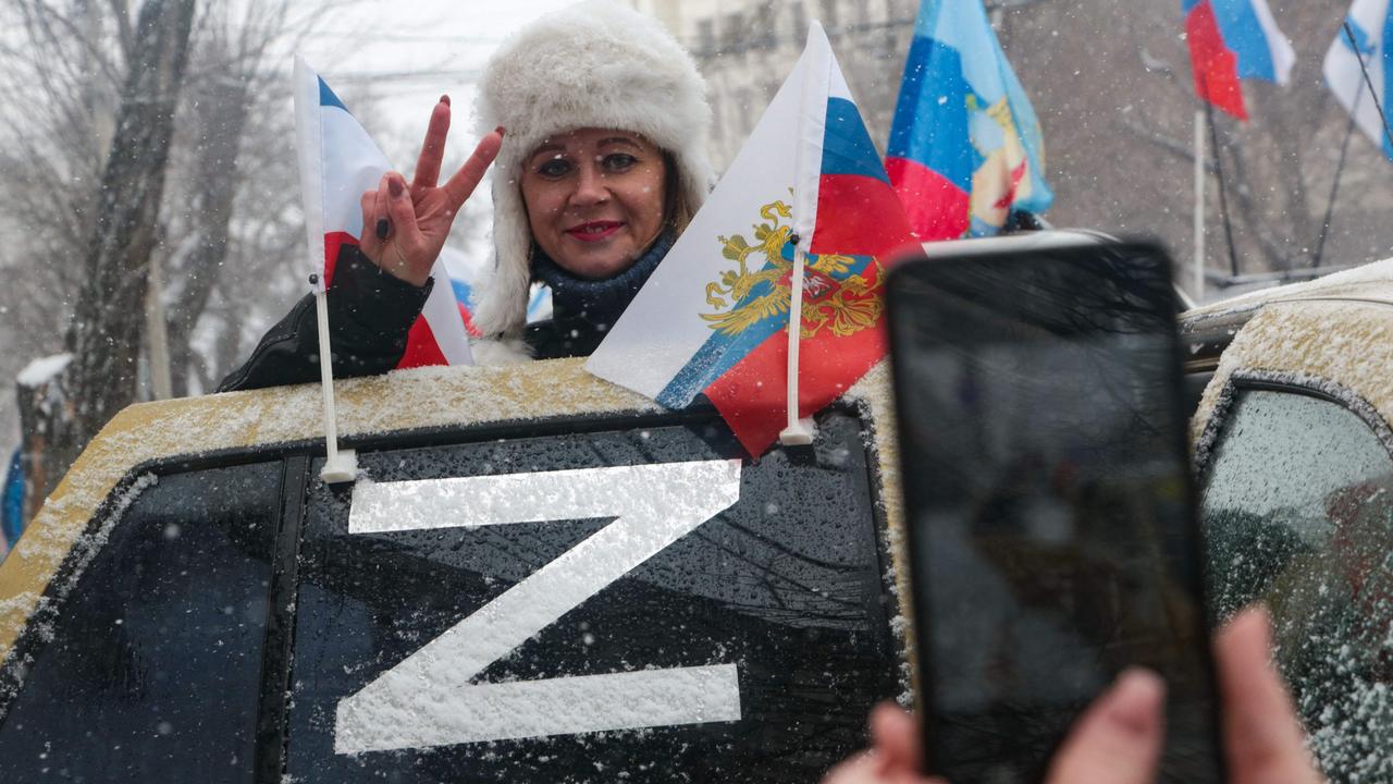 A woman poses for pictures from behind a car door with its window decorated with the ‘Z’ symbol letter "Z" Simferopol. Picture: Stringer/AFP