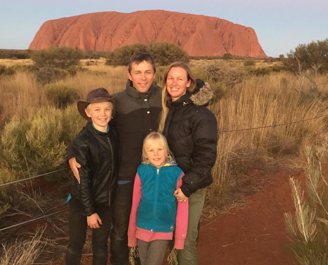 The family in front of some sort of large rock.