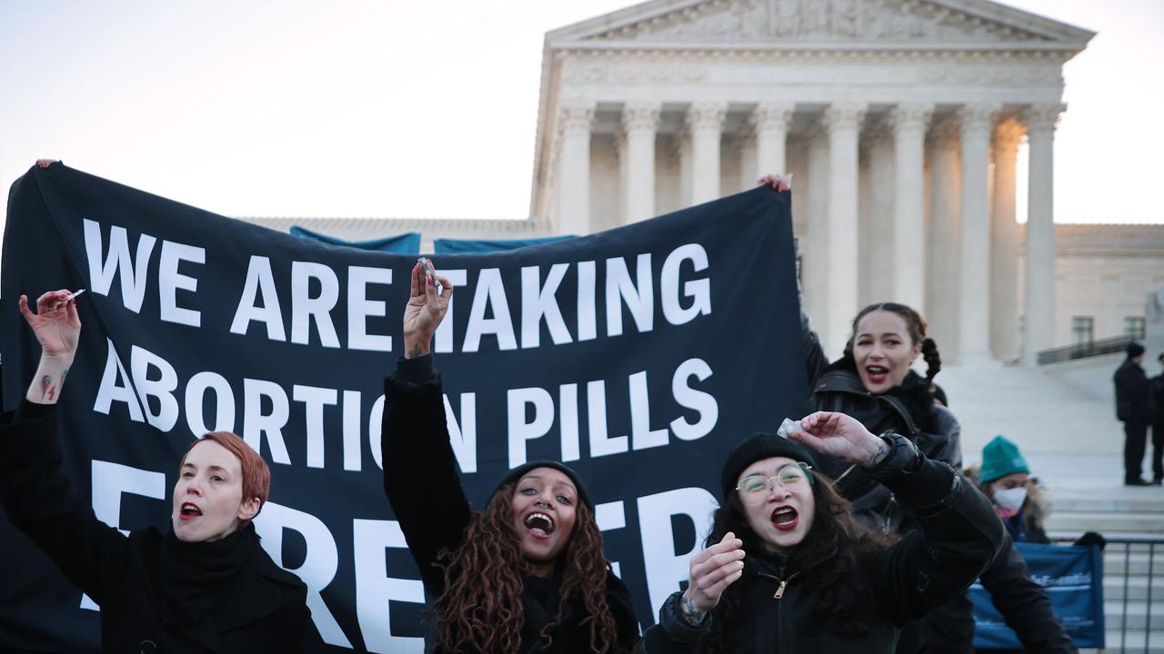 Lila Bonow, Alana Edmondson and Aiyana Knauer prepare to take abortion pill while demonstrating in front of the US Supreme Court. Picture: Chip Somodevilla/Getty Images