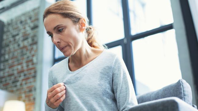 Gradual process. Beautiful mature woman touching sweater and having hot flash