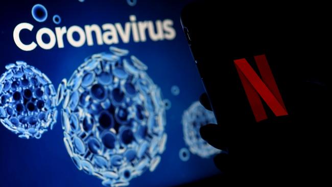 A mobile phone screens display the Netflix logo next to a coronavirus, COVID-19, illustration graphic background in Arlington, Virginia (Photo by Olivier DOULIERY / AFP)